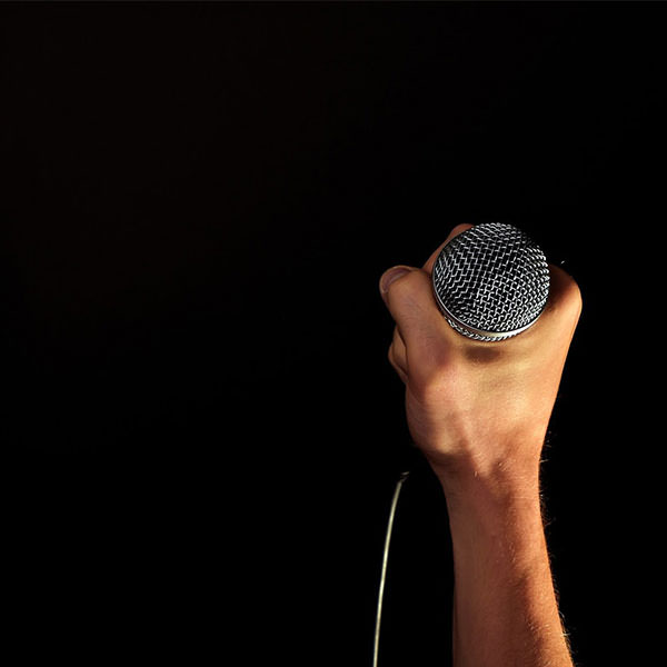 une main tient un micro de journaliste sportif sur le fond est noir