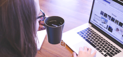 une étudiante travaille son Master Communication Digitale avec son ordinateur portable et sa tasse de café